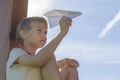 Boy flying a paper plane against blue sky. Summer day. Low angle view Royalty Free Stock Photo