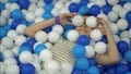 The boy fools around in the pool with colorful plastic balls and throws them Royalty Free Stock Photo