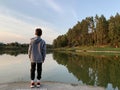 Boy on a forest lake. A child on a wooden pier by the river. A young man on the shore of a reservoir Royalty Free Stock Photo