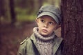 The boy in the forest is leaning against a tree trunk. Royalty Free Stock Photo