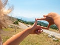 Boy is framing by fingers wooden tourist sign at gravel road to hill peak Royalty Free Stock Photo