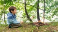 Boy fries bread on a skewer by the fire in a family camp. Survival lessons in the forest. Breakfast in the forest by the lake.