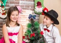 Boy gentleman and girl in ball dress by fireplace. Christmas