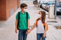 Boy and girl with backpacks and masks go to school in the coronavirus pandemic Royalty Free Stock Photo