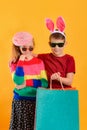 Boy with a girl in bright and colored clothes with shopping bags, concept of children`s shopping Royalty Free Stock Photo