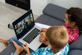 Boy and girl, brother and sister study at home. A girl watches a video lesson or an online conference, a boy does