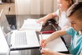 Boy and girl, brother and sister study at home. Children are sitting at a table with open notebooks and a laptop Royalty Free Stock Photo