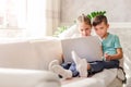 Boy and girl, brother and sister watching a video together on a laptop while sitting on a sofa at home Royalty Free Stock Photo