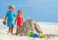 Boy and girl build sand castle putting feather on top at a beach Royalty Free Stock Photo