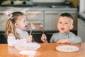 Boy and girl children in the kitchen eating sausages with pasta is very fun and friendly Royalty Free Stock Photo