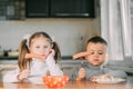 Boy and girl children in the kitchen eating sausages with pasta is very fun and friendly Royalty Free Stock Photo