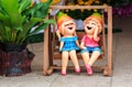 Boy and Girl Clay dolls in Wooden swings