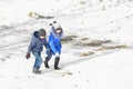 A boy and a girl climb a snow slide for sledding. Fun winter games Royalty Free Stock Photo