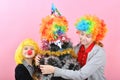 Boy and girl in clown wig hugs funny new year christmas tree in wig Royalty Free Stock Photo