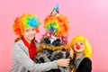 A boy and a girl in a clown wig are standing next to a funny Christmas tree wearing a wig Royalty Free Stock Photo