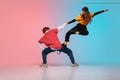 Boy and girl dancing hip-hop in stylish clothes on gradient background at dance hall in neon light. Royalty Free Stock Photo