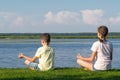 Boy and girl doing yoga outdoors by the lake Royalty Free Stock Photo