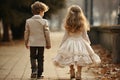 a boy and a girl dressed as the bride and groom walk along a path in the park, rear view Royalty Free Stock Photo