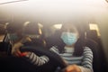 Boy and girl driving a car wearing sterile medical mask. Taxi driver with a passanger stuck in a traffic jam during coronavirus