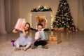 Boy and girl family opens Christmas gift new year holiday lights Christmas tree garlands Royalty Free Stock Photo