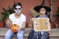 Boy and girl in Halloween costumes sitting at the entrance of their house