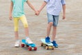 Boy and girl hold hands and want to ride skateboards together