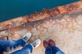 A boy with a girl in jeans and keds stands on a rusty pier.