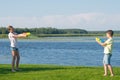 Boy and girl on the lake, on the green grass, playing water pistols, pointing them at each other Royalty Free Stock Photo