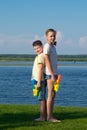 Boy and girl on the lake, holding water pistols and stand with their backs to each other, against a beautiful landscape Royalty Free Stock Photo