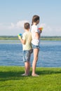 Boy and girl on the lake, holding water pistols and stand with their backs to each other, against a beautiful landscape, looking Royalty Free Stock Photo
