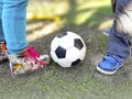 Boy and girl legs with soccer ball on spring green grass. Royalty Free Stock Photo