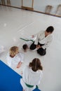 Boy and girl looking at their aikido trainer doing hack on boy