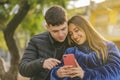 Boy and girl in love sitting on a bench in a public park looking at a mobile phone Royalty Free Stock Photo