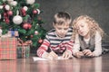 Boy and girl lying on the floor under Christmas tree Royalty Free Stock Photo