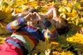 A boy and a girl are lying on yellow leaves in an autumn park. Royalty Free Stock Photo