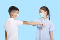 Boy and girl in medical mask bumping their elbows.Isolated on blue background