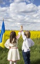 boy girl in national Ukrainian clothes, holding hands, standing in blooming yellow field of rapeseed Royalty Free Stock Photo