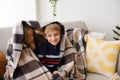 Boy and girl, an older sister and younger brother, are sitting under blanket on sofa, secreting, dreaming, hugging Royalty Free Stock Photo