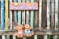 Boy and girl plaster dolls sitting on the swings which showing a plate in Thai alphabets