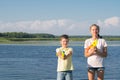 Boy and girl play water pistols against the blue lake and sky Royalty Free Stock Photo