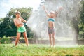 Boy and girl playing in garden, pouring with water each other from the hose, making a rain. Happy childhood concept image Royalty Free Stock Photo