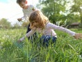 Boy and girl are playing in the meadow. Children lean in the green grass and touch it with their hands. Brother and sister walk in Royalty Free Stock Photo