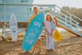 Boy and girl posing with surfboards against blue lifeguard tower on the beach. Royalty Free Stock Photo