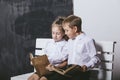 Boy and girl from primary school class on the bench read books o Royalty Free Stock Photo