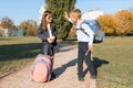 Boy and girl, primary school students with backpacks go to school. Sunny day background, road in the park