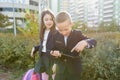 Boy and girl pupils in primary school with digital tablet. Outdoor background, children with school bags, look at the tablet