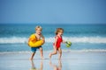 Boy with girl run holding inflatable buoys duck and toy at beach Royalty Free Stock Photo