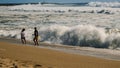 A boy and a girl are running from the coming waves. Foaming waves of the Atlantic Ocean. View from the coast Royalty Free Stock Photo