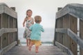 Boy and girl running on wooden boardwalk on the beach Royalty Free Stock Photo