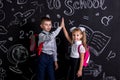 Boy and girl. School mates standing before the chalkboard as a background with a backpack on their backs claping their